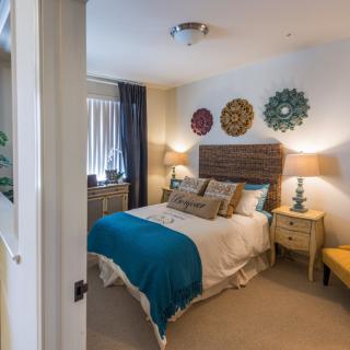 A cozy bedroom with a neatly made bed, decorative wall hangings, and warm lighting.