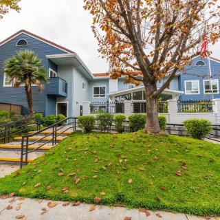 A two-story residential building with a well-maintained lawn and trees in the foreground.