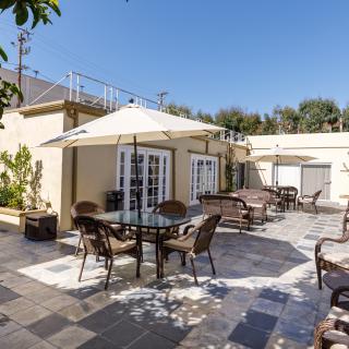 A sunny patio with tables, chairs, and umbrellas for outdoor seating.