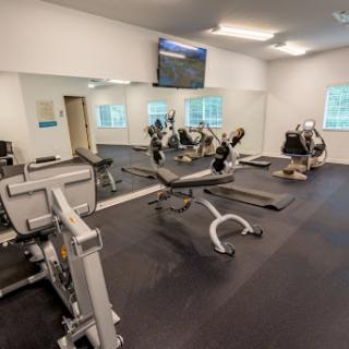 A modern gym equipped with various exercise machines and a wall-mounted TV.