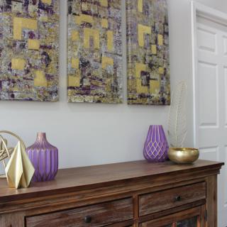 A stylish interior featuring a wooden sideboard adorned with decorative vases and modern artwork.