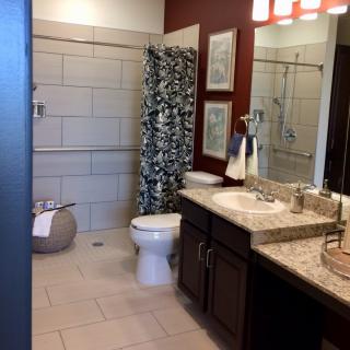 A modern bathroom with a countertop sink, toilet, and patterned shower curtain.
