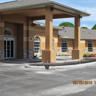A commercial building with a covered entrance and surrounding parking area.