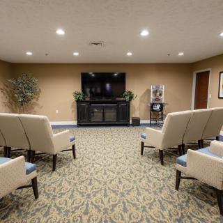 A cozy seating area with chairs arranged facing a large TV, in a carpeted room.