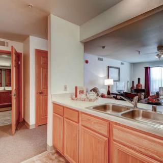 An open-plan kitchen area with a double sink leading to a cozy living room.