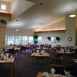 A spacious dining area with neatly arranged tables and chairs, well-lit by large windows.