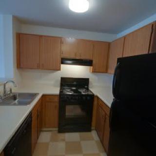 A kitchen with wooden cabinets, a black stove, and a sink.