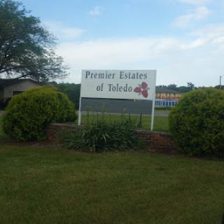 Welcome sign for 'Premiere Estates at Toledo' surrounded by greenery.