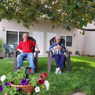 Two people sitting in chairs, relaxing in a garden surrounded by flowers.