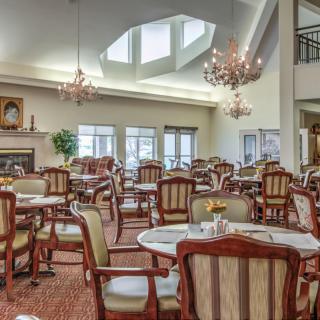 A spacious and elegant dining room with multiple tables and chandeliers.