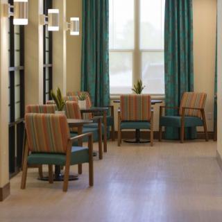 A modern lobby seating area with chairs and tables arranged by large windows.