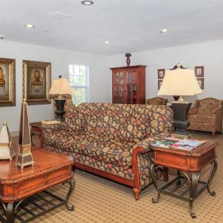 A traditional living room with patterned sofas, wooden tables, and decorative paintings.