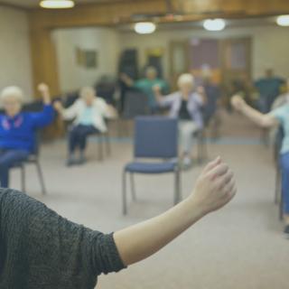 A group of seniors participating in an indoor exercise class.