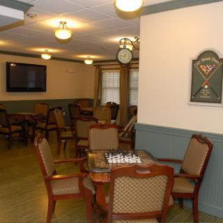 A cozy game room featuring a chess board, dartboard, seating area, and a television.
