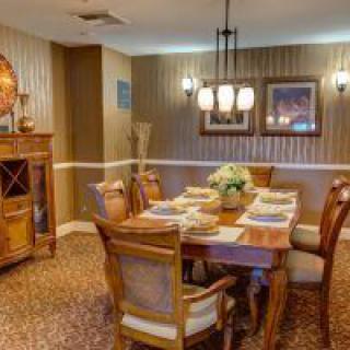 A cozy dining room with a wooden table and chairs, adorned by a chandelier and decorated walls.
