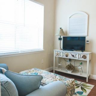 A cozy living room corner with a sofa and TV stand next to a window providing ample natural light.