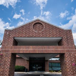 A brick building entrance under a blue, cloudy sky.