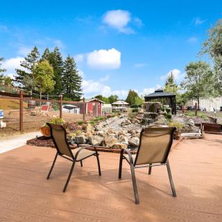 A tranquil outdoor patio area with two chairs facing a landscaped garden featuring rocks and trees under a clear blue sky.