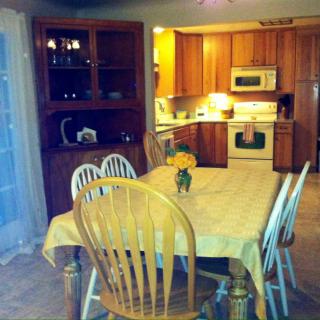 A cozy dining area adjacent to a kitchen featuring wooden furniture and floral decorations.