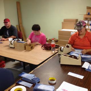 A group of individuals working together at a table, engaged in packaging tasks.
