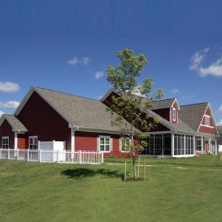 A charming red house with a green lawn under a clear blue sky.