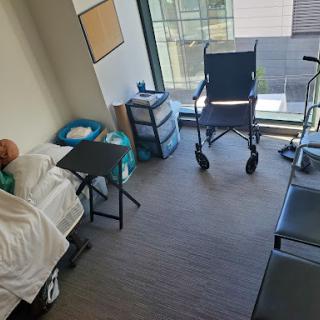 A view of a hospital room equipped with a bed, a wheelchair, and other medical furnishings.