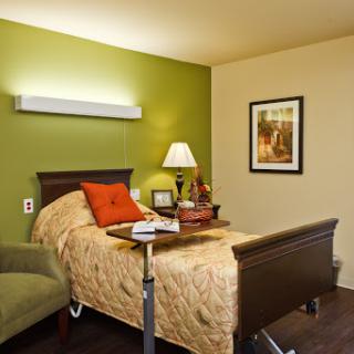 A cozy bedroom featuring a bed with decorative pillows, a bedside lamp, and a comfortable chair.