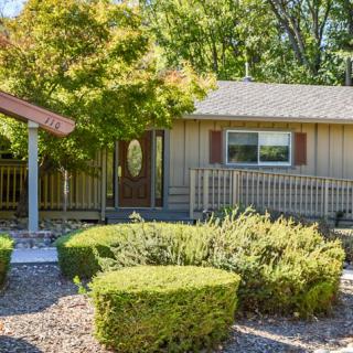 A cozy single-story house with a well-maintained garden and trimmed bushes.