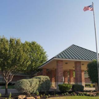A well-kept building with a flag flying in the clear blue sky.