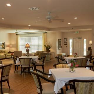 A cozy dining room with elegantly arranged tables and chairs, featuring warm lighting and inviting decor.