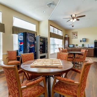 A bright community room with tables, chairs, and vending machines.