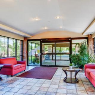 A modern lobby area featuring red sofas, glass doors, and indoor plants.