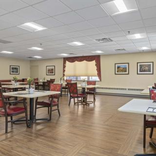 A well-lit dining area with neatly arranged tables and chairs, featuring framed artwork on the walls.