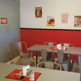 A cozy diner with red and gray decor, featuring vintage wall art and metal seating.