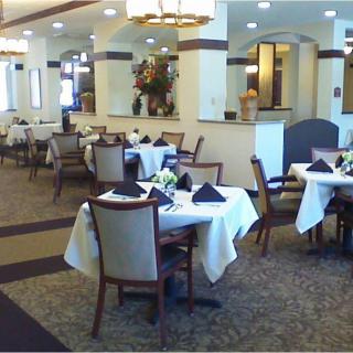 An elegant restaurant dining area with neatly arranged tables and chairs, featuring formal table settings.