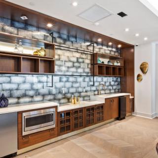 A modern kitchen featuring wood cabinetry, built-in appliances, and a striking brick backsplash.