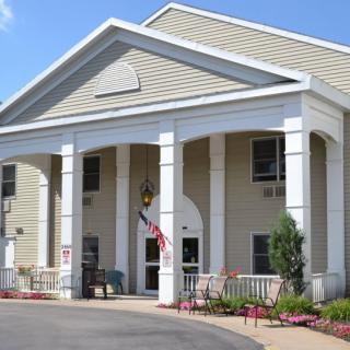 A building entrance with large columns and a neatly landscaped area.