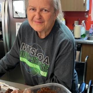 A person smiling in a kitchen while preparing food.