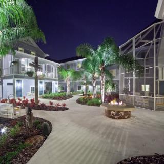 A serene nighttime courtyard with palm trees and a cozy fire pit.