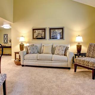 A cozy living room with a beige sofa, accent chairs, and warm lighting.