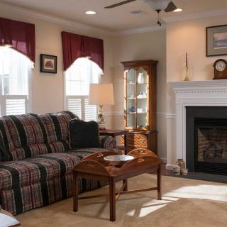 A cozy living room with a striped sofa, fireplace, and wooden coffee table.