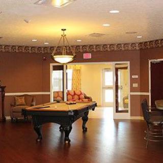 A cozy billiard room featuring a pool table, elegant chandelier, and comfortable seating on wooden floors.