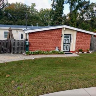 A small brick house with a fenced yard and surrounding trees.