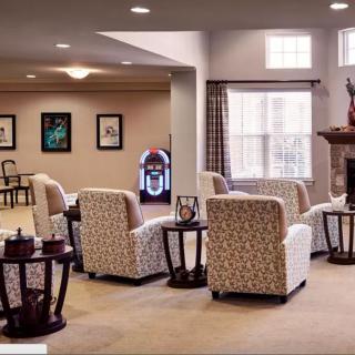 A cozy living room with patterned chairs, a fireplace, and large windows.