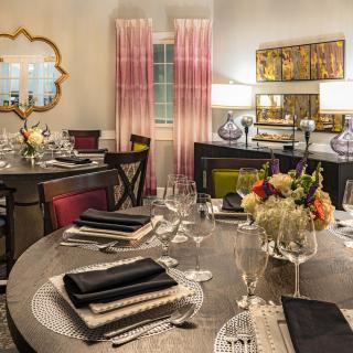 A stylish dining room featuring an elegantly set table with black and white napkins, floral centerpiece, and sophisticated decor.