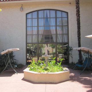 An outdoor scene featuring a large window with reflections, flanked by umbrellas and a planter filled with green plants.