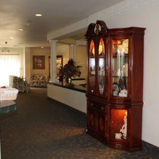 A well-lit hallway featuring an elegant wooden cabinet with glass doors, showcasing decorative items.