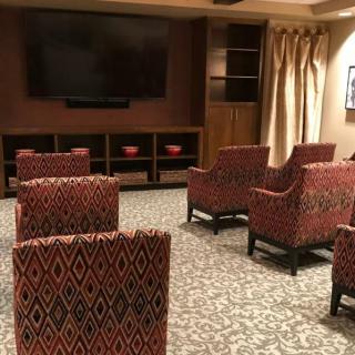 A cozy home theater setup with patterned chairs and a large screen.