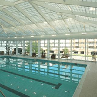 A spacious indoor swimming pool with a glass ceiling allowing natural light to flood the area.