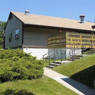 A house with a wooden ramp and well-maintained lawn under a clear blue sky.